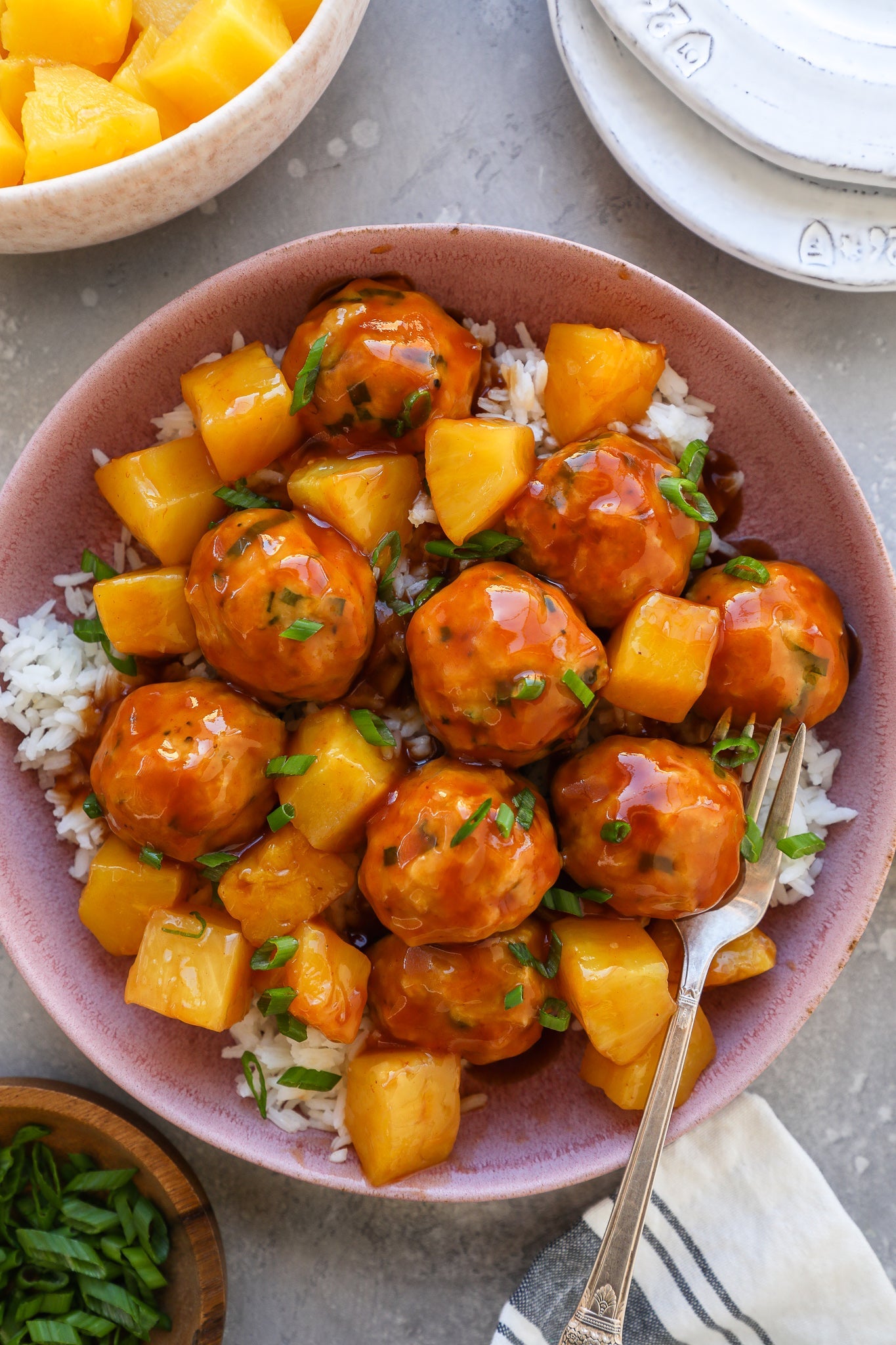 A bowl of sweet and sour chicken meatballs over rice, beside a bottle of Fody's no onion no garlic ketchup