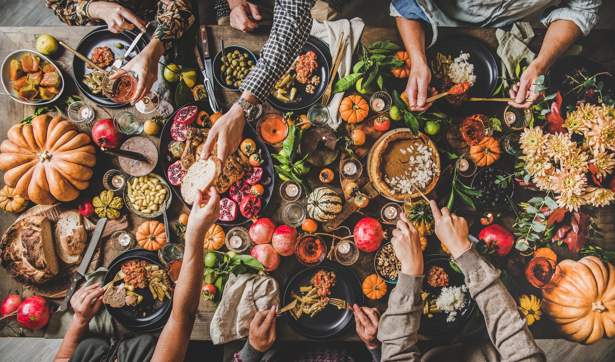 A bird’s-eye view of a healthy Thanksgiving dinner table spread with pies, roast chicken and decorative pumpkins.