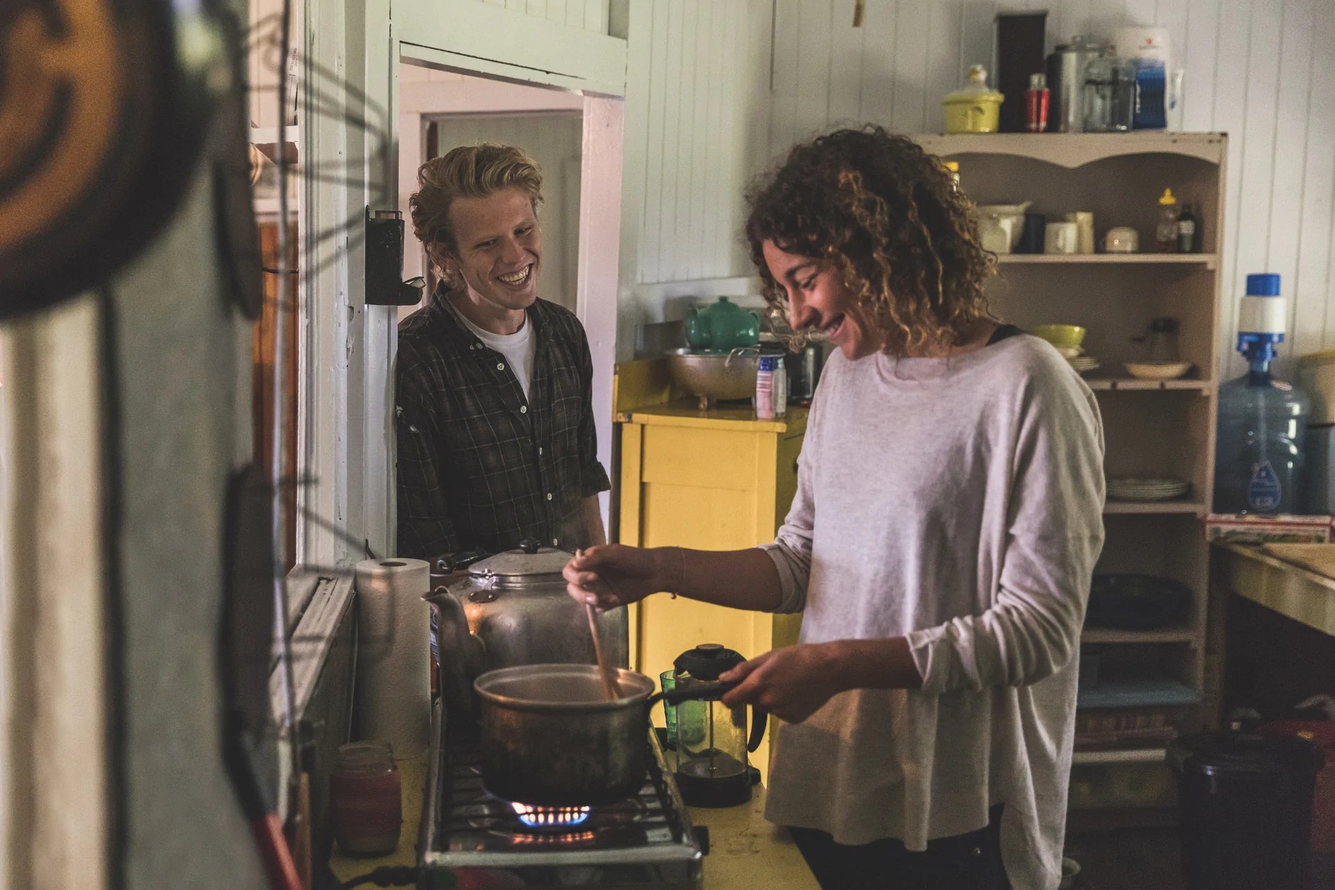 A young couple preparing gut healthy comfort food in a cozy kitchen and laughing together.