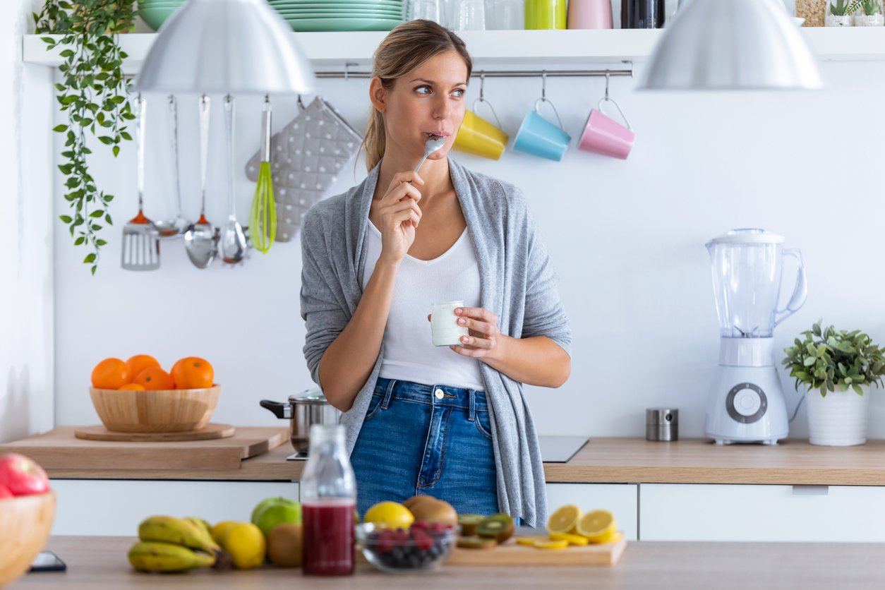 Girl with spoon in mouth next to a table full of fruit