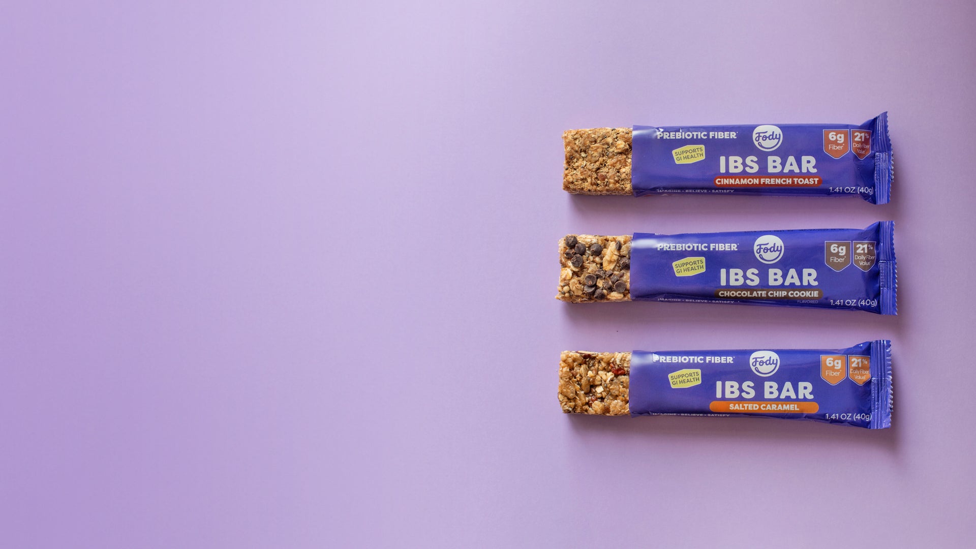 Three Fody IBS Bars in purple wrappers—Cinnamon French Toast, Chocolate Chip Cookie, and Salted Caramel—arranged on a light purple background.