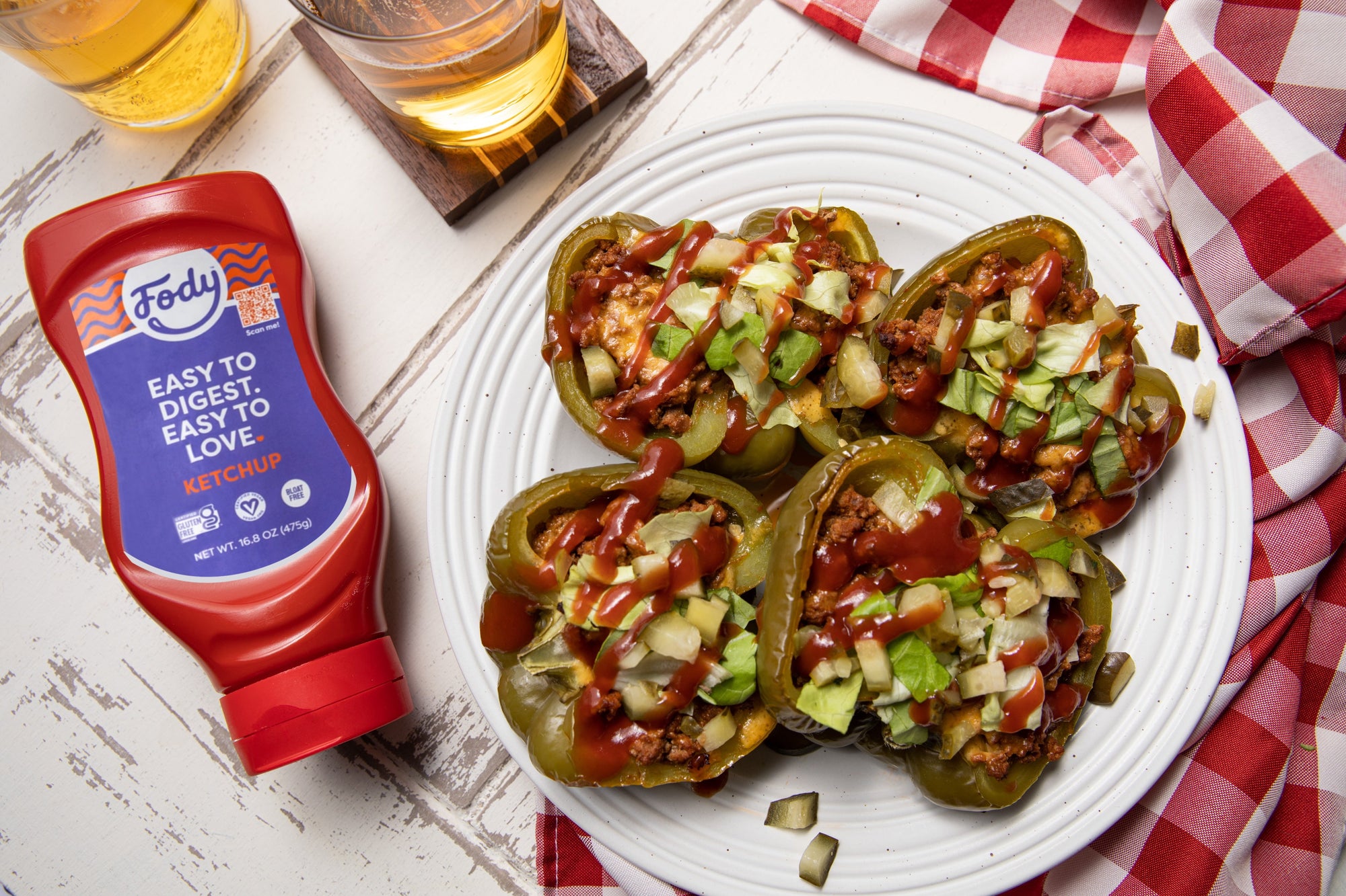 Two of Fody’s Cheese Stuffed Peppers on a plate beside a bottle of Fody’s Ketchup.