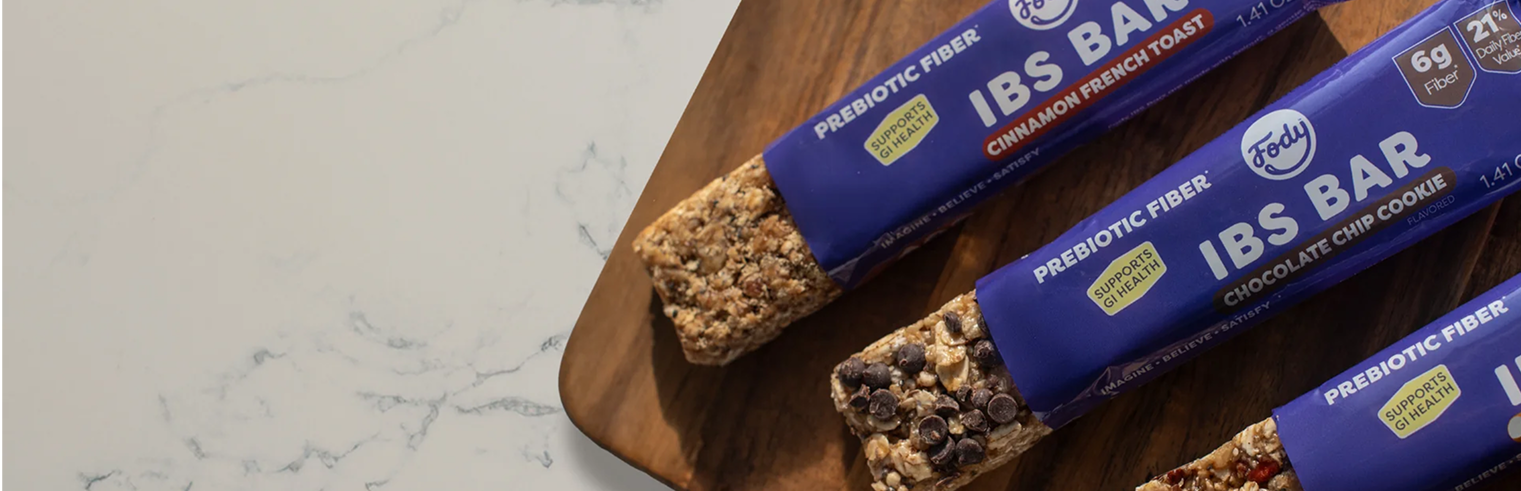 Fody Low FODMAP snack bars arranged on a wooden surface, showing a selection of certified bar varieties suited for IBS management.