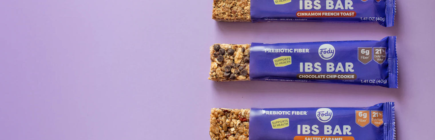 Person pulling a Fody Dark Chocolate Nuts and Sea Salt Low FODMAP snack bar from a backpack outdoors — gut-friendly and on-the-go.