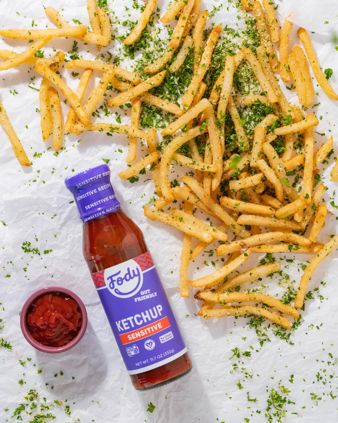 Fody Sensitive Ketchup bottle with golden French fries and a side of ketchup on white parchment paper.