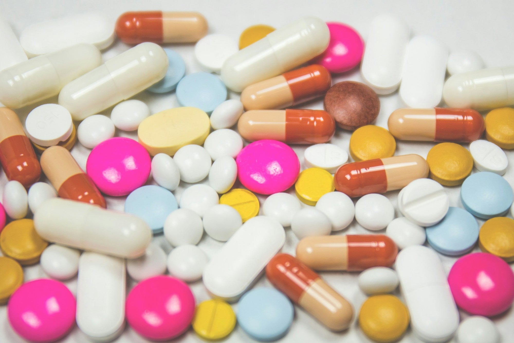An assortment of colorful capsules and tablets spread across a white surface, representing the gut health supplement categories compared in an IBS supplement guide.