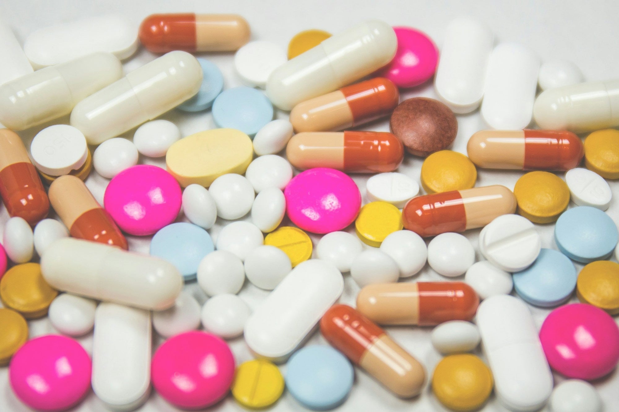 An assortment of colorful capsules and tablets spread across a white surface, representing the gut health supplement categories compared in an IBS supplement guide.