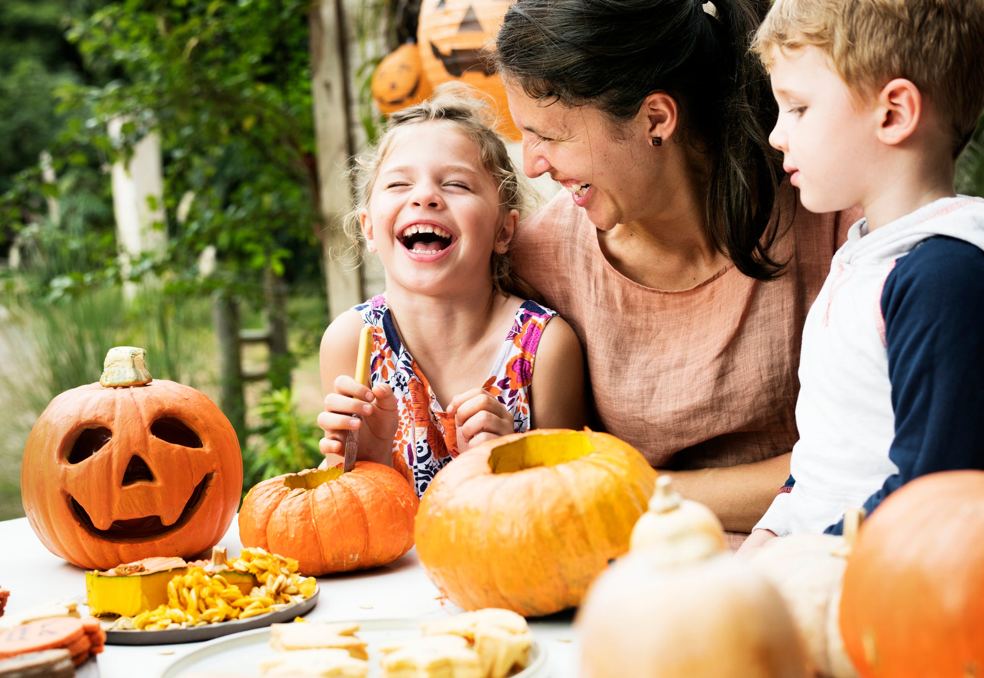 Two younger children and their mother enjoying gut-healthy Halloween treats while carving pumpkins.