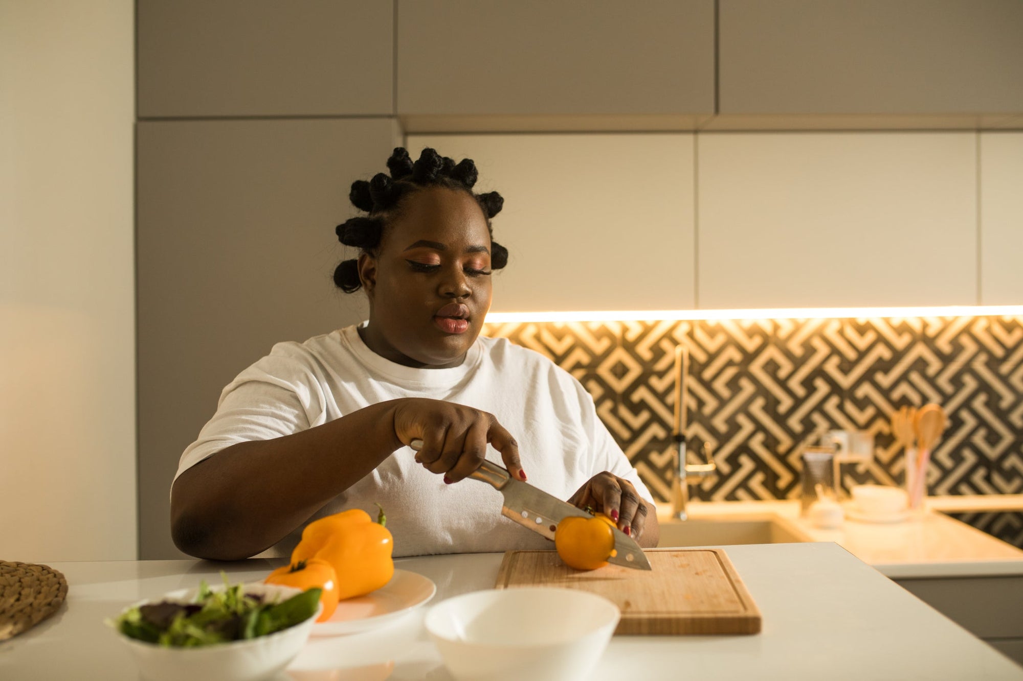 A woman preparing breakfast before a full day of eating for gut health, cutting an orange on her kitchen counter.