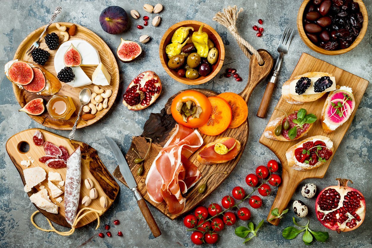 A holiday snack platter spread: marinated olives, meats, low FODMAP cheese and fruits and vegetables on a gut-friendly low-FODMAP charcuterie board.