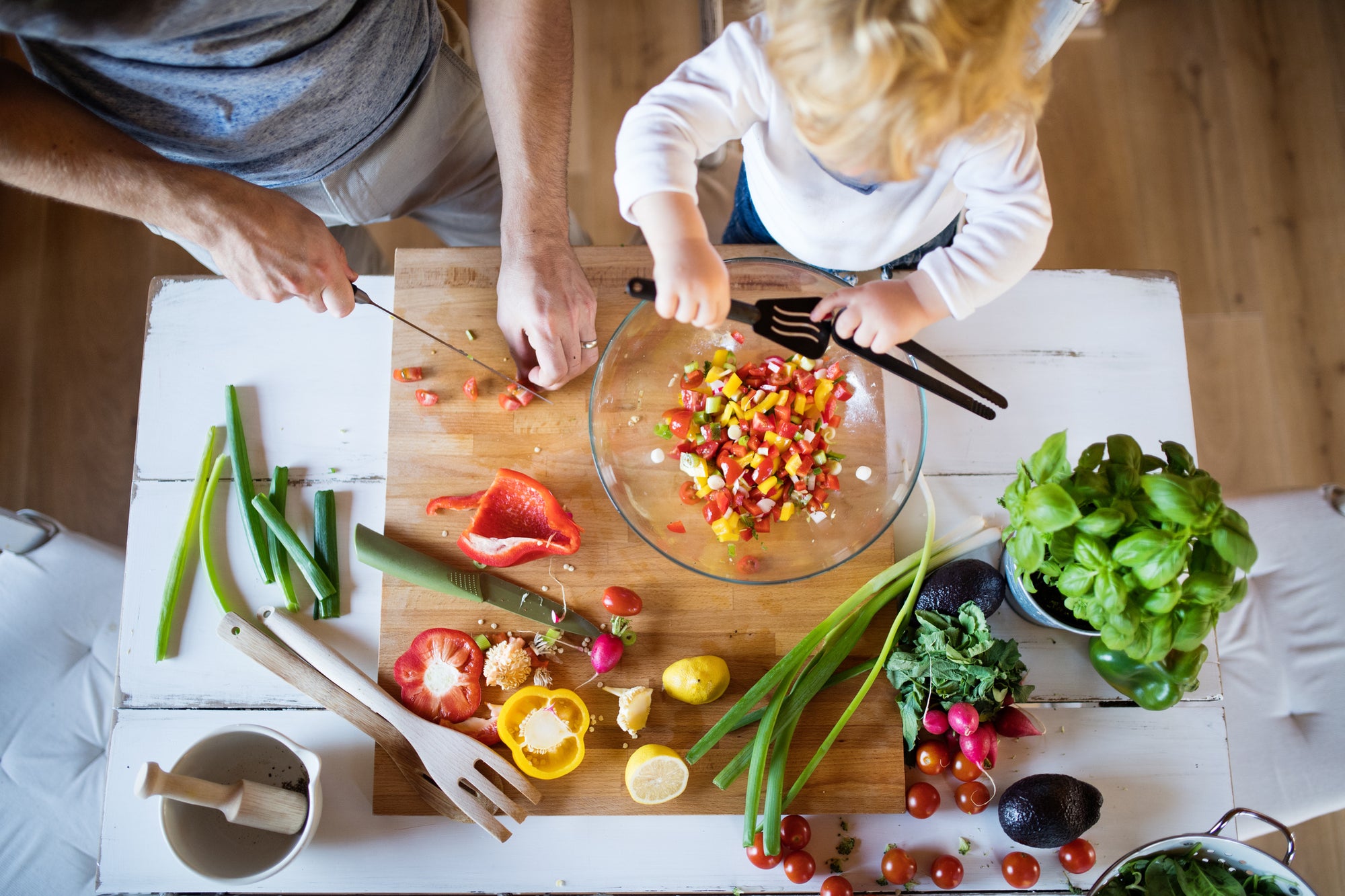 An aerial view of a father and toddler preparing a salad, one of Fody’s healthy lunch ideas for kids.