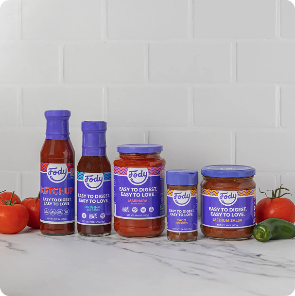 Fody pasta sauce jars and dressing bottles lined up on a kitchen counter, pantry staples for building Low FODMAP lunches ahead of time