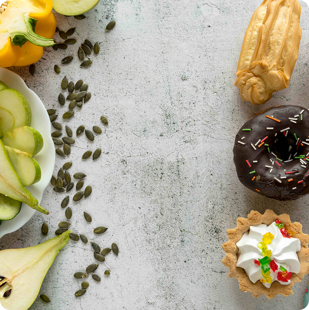 Flat lay of green foods on gray stone, with kiwi slices, avocado halves, leafy greens, and other fresh produce arranged in loose rows
