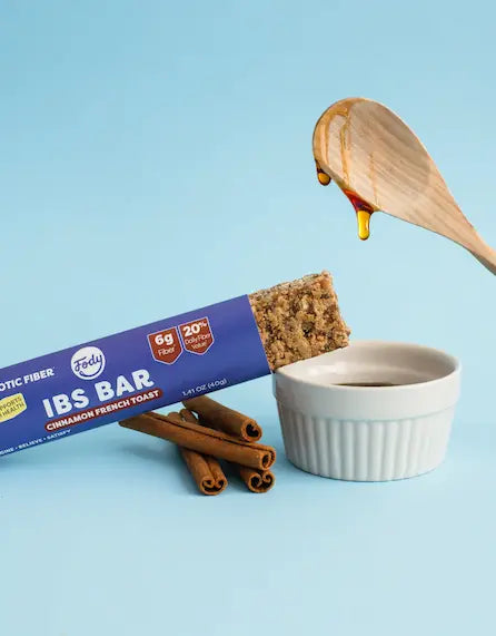 Four Fody snack bars on purple, each below a row of a key ingredient: peanuts, dark chocolate squares, coconut flakes and fresh blueberries